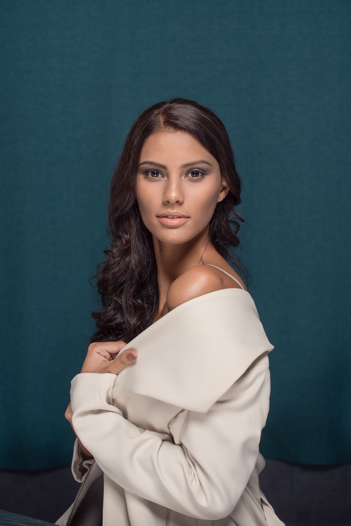 Woman in a cream off-shoulder jacket against a teal background — studio portrait photography in Cape Town