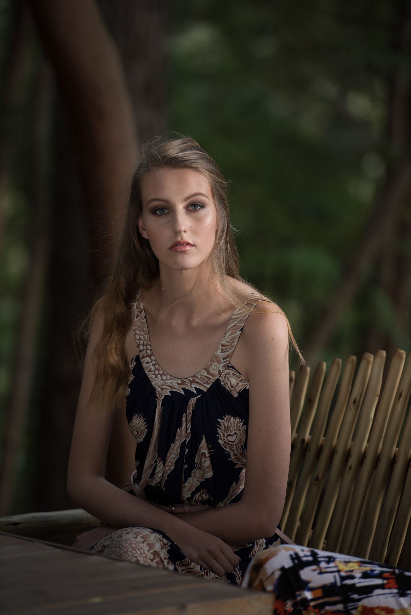 Blonde woman in a patterned dress by a bamboo fence — outdoor portrait photography in Cape Town